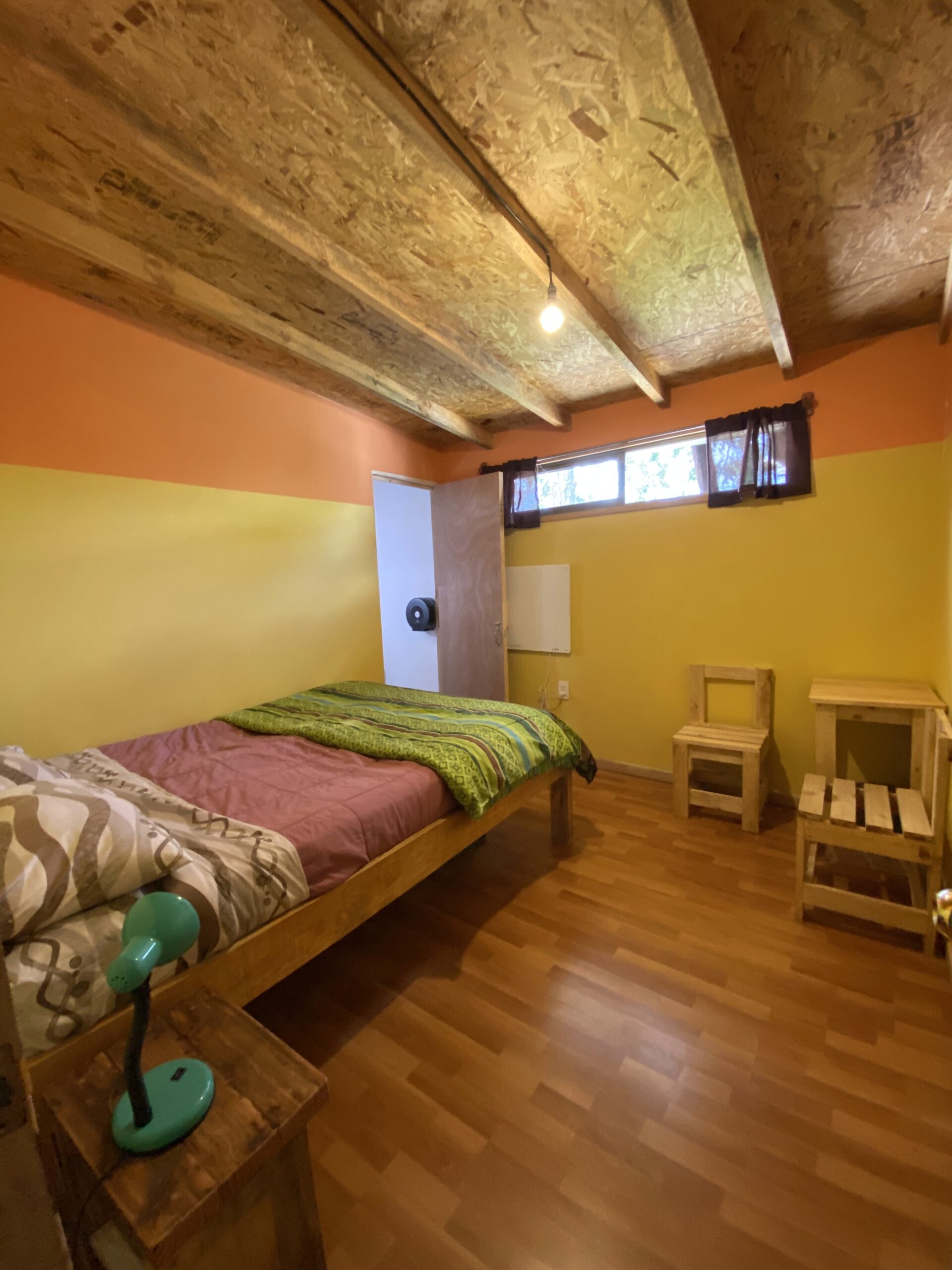 Habitación piso de madera, cama matrimonial con baño privado, mesa, sillas y calefacción
